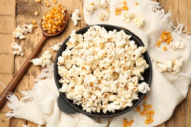 Photo of Tasty popcorn and corn kernels on wooden table, flat lay