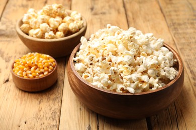 Photo of Tasty popcorn and corn kernels on wooden table, closeup