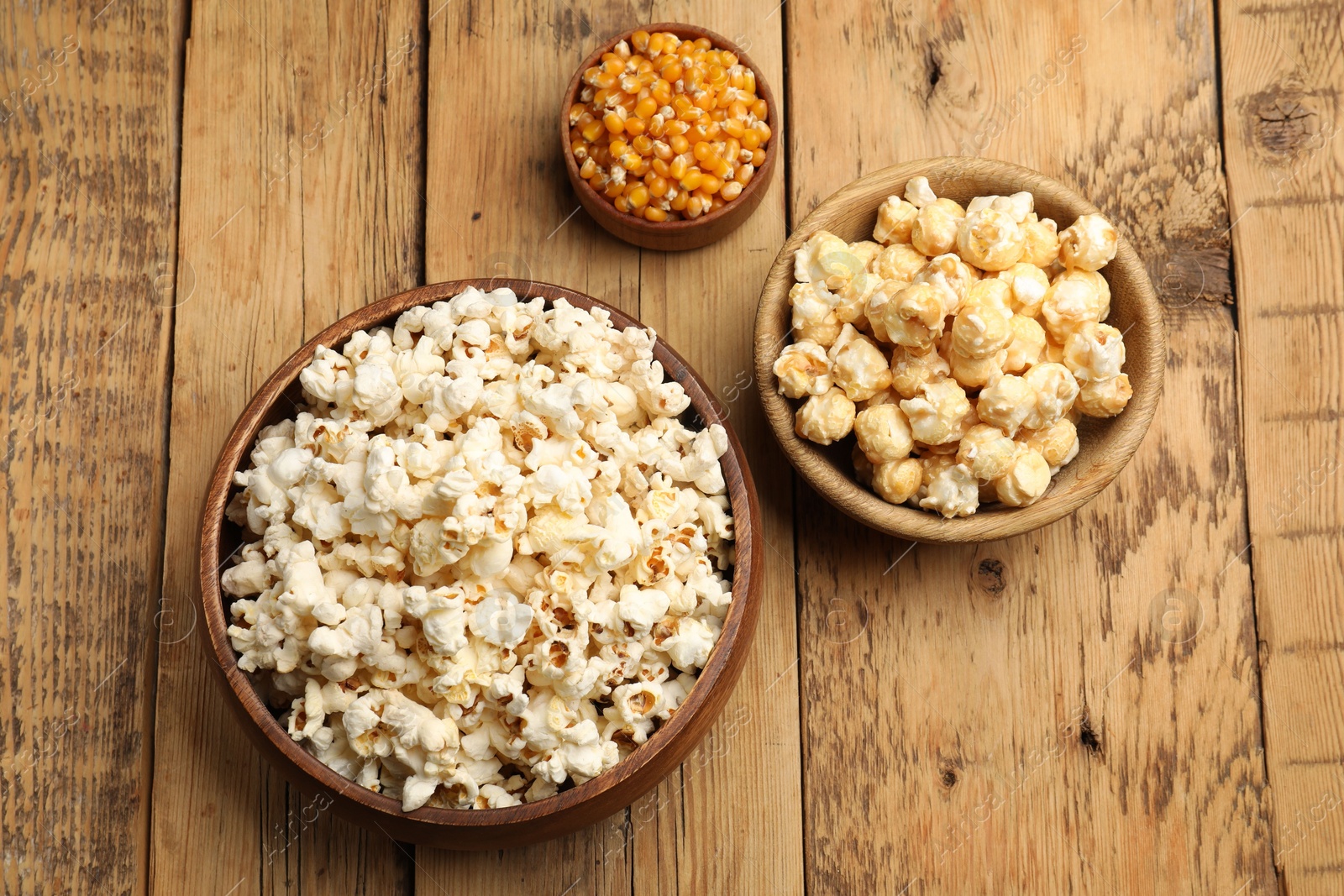 Tasty popcorn and corn kernels on wooden table, flat lay Photo of Tasty popcorn and corn kernels on wooden table, flat lay