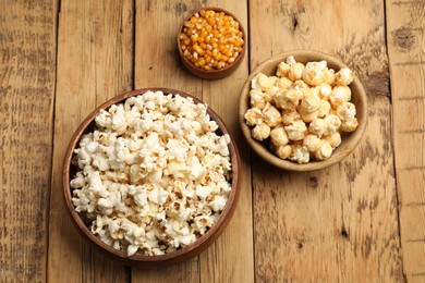 Photo of Tasty popcorn and corn kernels on wooden table, flat lay