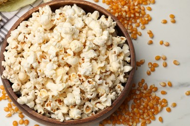 Photo of Tasty popcorn and corn kernels on white table, flat lay