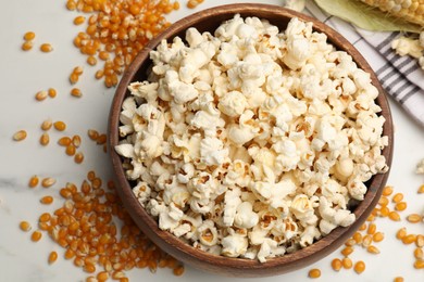 Photo of Tasty popcorn and corn kernels on white table, flat lay