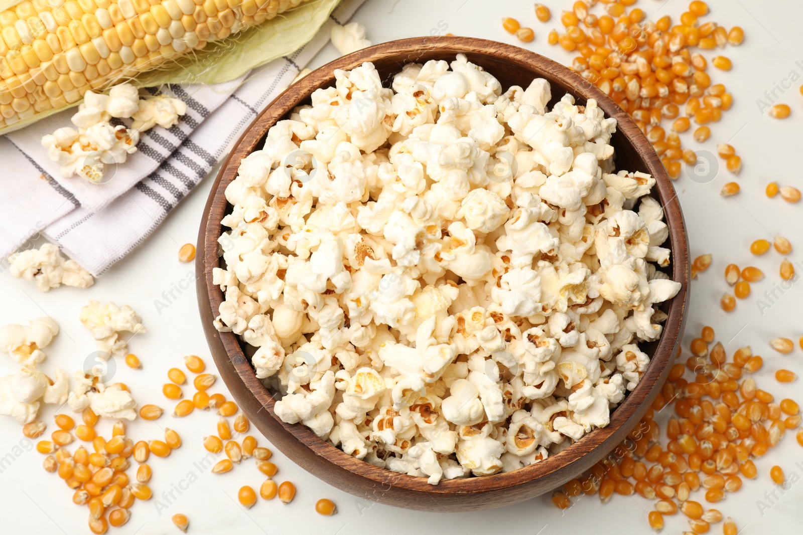 Tasty popcorn and corn kernels on white table, flat lay Photo of Tasty popcorn and corn kernels on white table, flat lay
