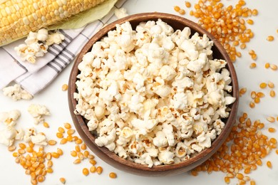 Photo of Tasty popcorn and corn kernels on white table, flat lay