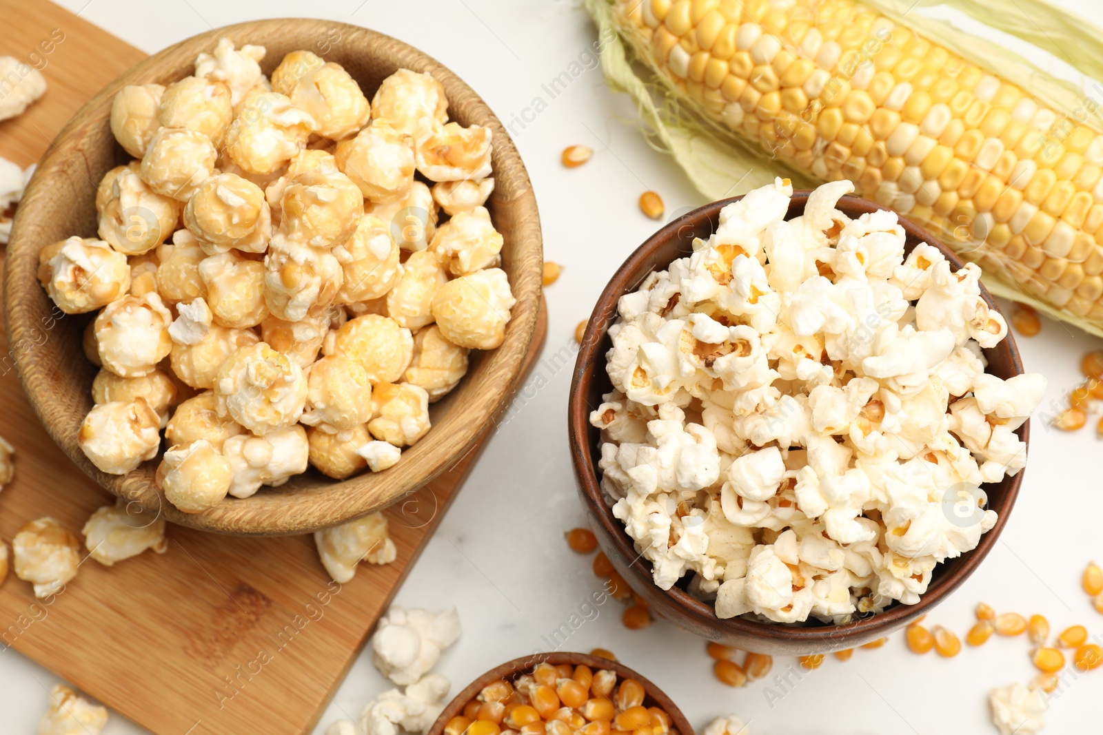 Tasty popcorn and corn kernels on white table, flat lay Photo of Tasty popcorn and corn kernels on white table, flat lay