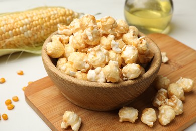 Photo of Tasty popcorn and corn kernels on white table, closeup
