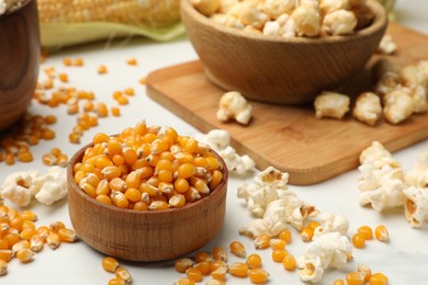 Photo of Corn kernels and tasty popcorn on white table, closeup
