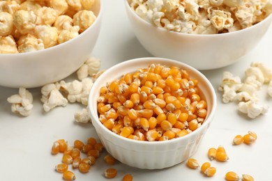 Photo of Corn kernels and tasty popcorn on white table, closeup