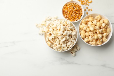 Photo of Tasty popcorn and corn kernels on white table, flat lay. Space for text
