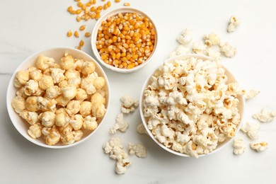 Photo of Tasty popcorn and corn kernels on white table, flat lay