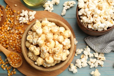 Photo of Tasty popcorn and corn kernels on blue wooden table, flat lay
