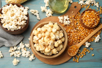 Photo of Tasty popcorn and corn kernels on blue wooden table, flat lay