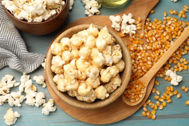 Photo of Tasty popcorn and corn kernels on blue wooden table, flat lay
