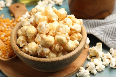 Photo of Tasty popcorn and corn kernels on blue wooden table, closeup