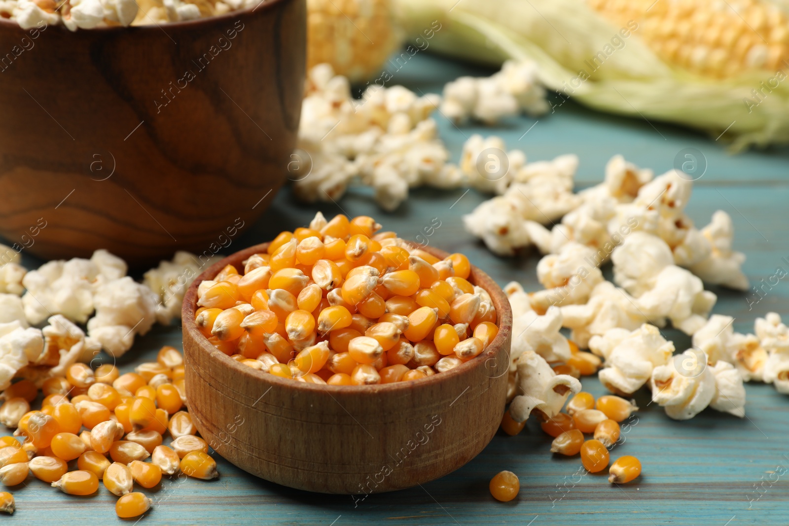 Corn kernels and tasty popcorn on blue wooden table, closeup Photo of Corn kernels and tasty popcorn on blue wooden table, closeup