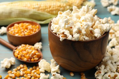 Photo of Tasty popcorn and corn kernels on blue wooden table, closeup