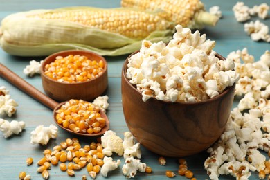 Photo of Tasty popcorn and corn kernels on blue wooden table, closeup