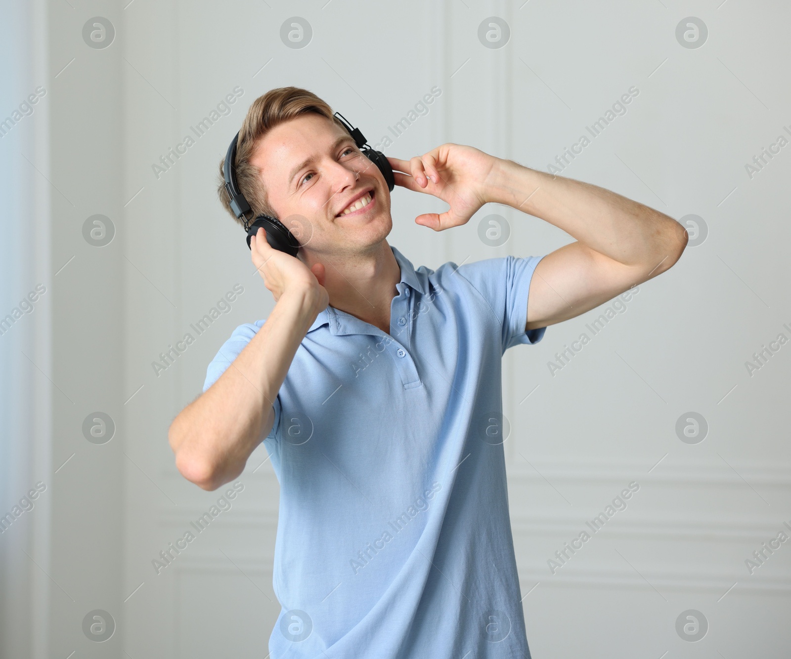 Happy man in headphones listening to music and dancing at home Photo of Happy man in headphones listening to music and dancing at home
