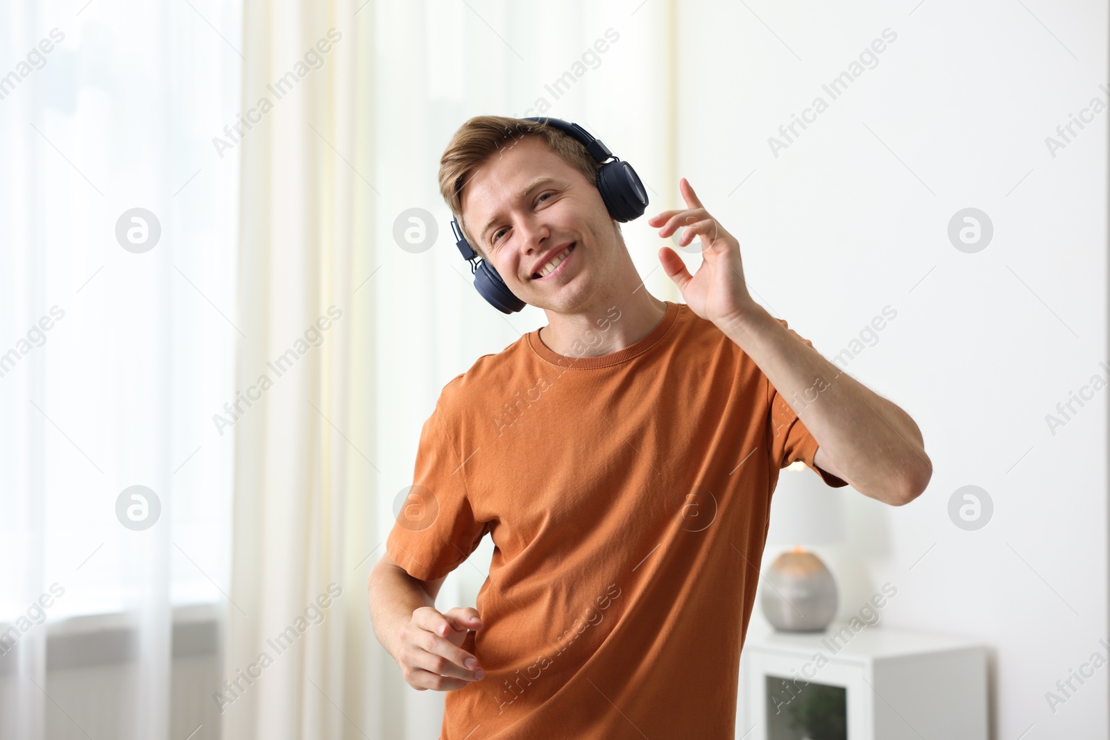 Happy man in headphones listening to music and dancing at home Photo of Happy man in headphones listening to music and dancing at home