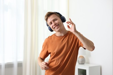 Photo of Happy man in headphones listening to music and dancing at home
