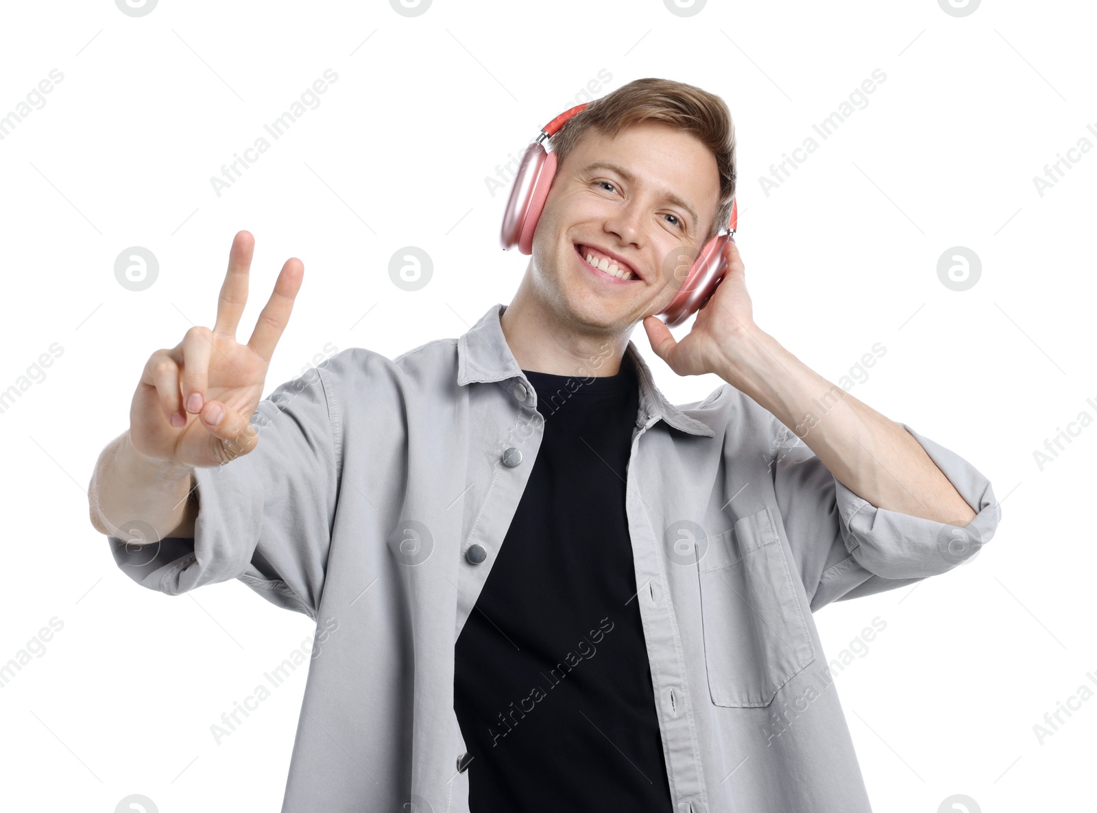 Happy man listening to music in headphones and showing peace sign on white background Photo of Happy man listening to music in headphones and showing peace sign on white background