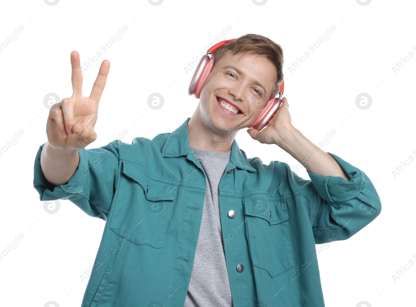 Happy man listening to music in headphones and showing peace sign on white background Photo of Happy man listening to music in headphones and showing peace sign on white background