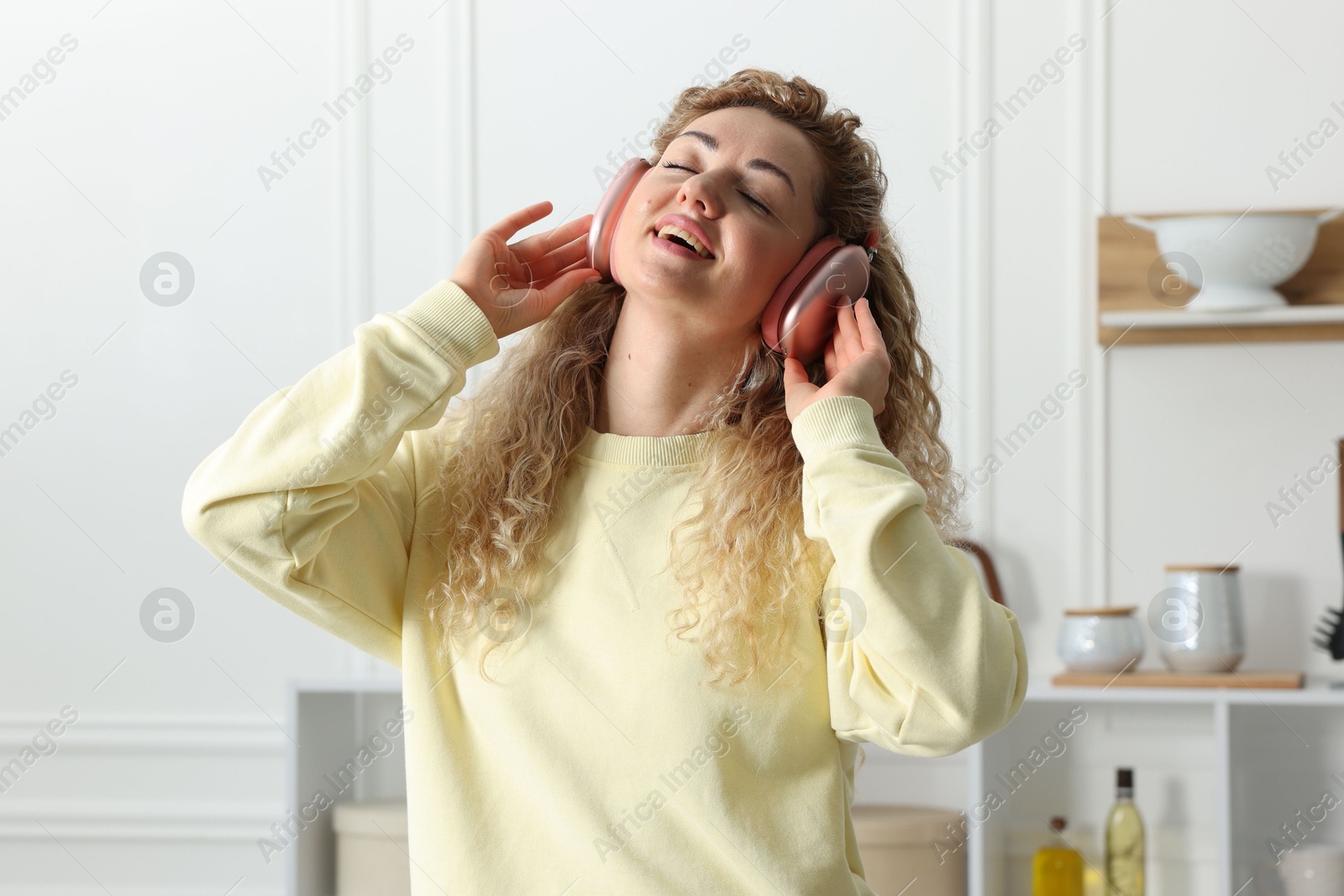 Photo of Happy woman in headphones listening to music and dancing at home