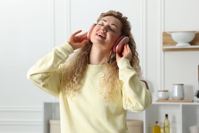 Photo of Happy woman in headphones listening to music and dancing at home
