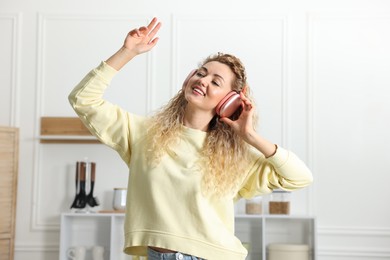 Photo of Happy woman in headphones listening to music and dancing at home