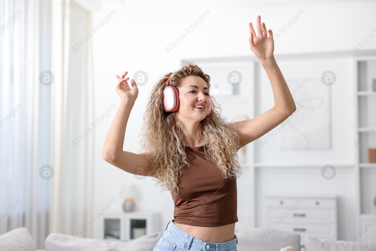 Photo of Happy woman in headphones listening to music and dancing at home
