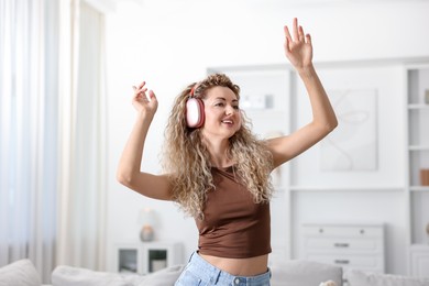 Photo of Happy woman in headphones listening to music and dancing at home