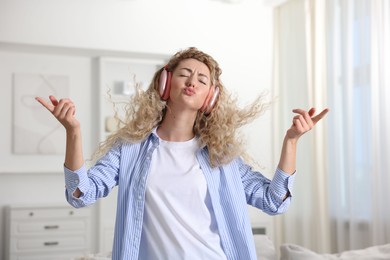 Photo of Happy woman in headphones listening to music and dancing at home