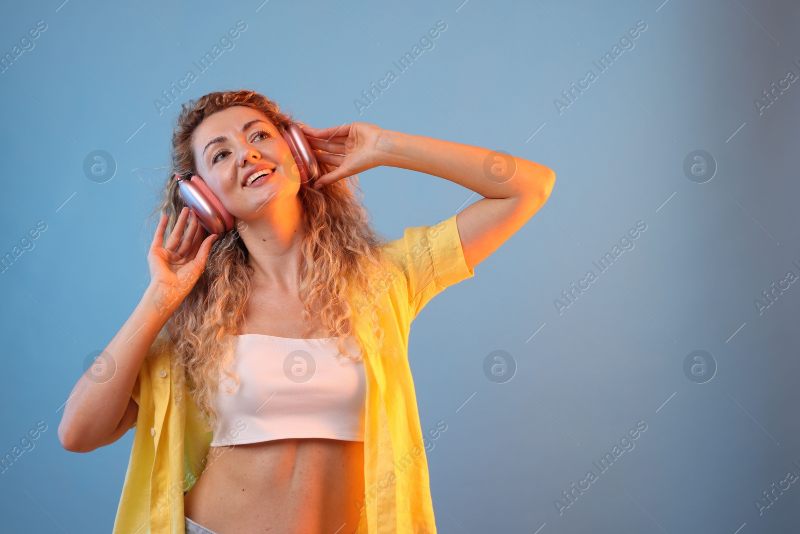 Happy woman listening to music in headphones and dancing on light blue background. Space for text Photo of Happy woman listening to music in headphones and dancing on light blue background. Space for text