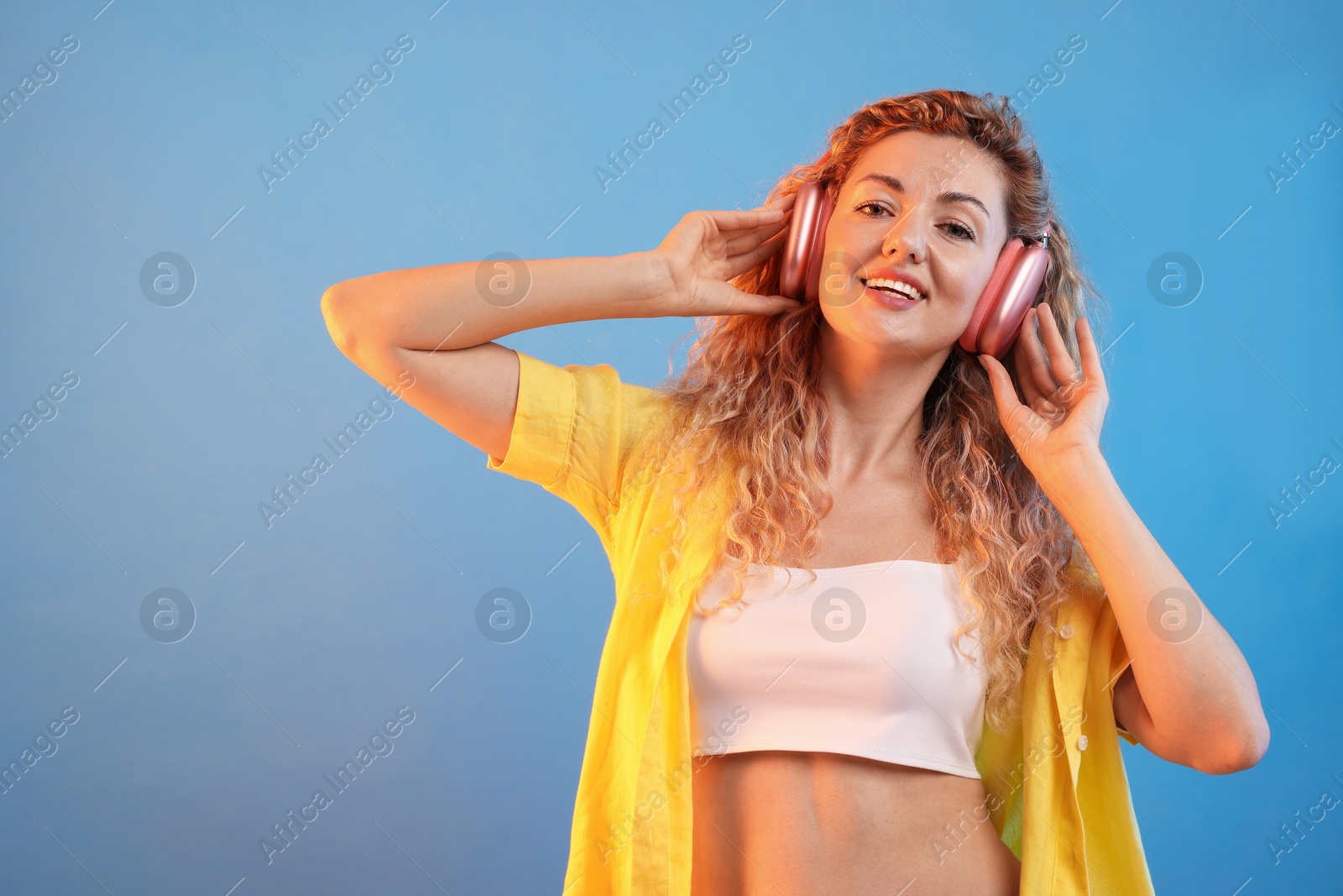 Happy woman listening to music in headphones and dancing on light blue background. Space for text Photo of Happy woman listening to music in headphones and dancing on light blue background. Space for text