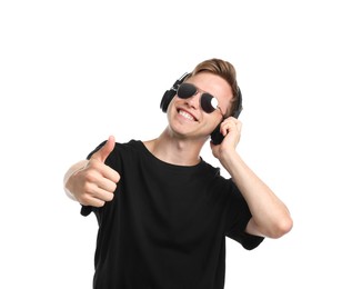Photo of Happy man listening to music in headphones and showing thumbs up on white background