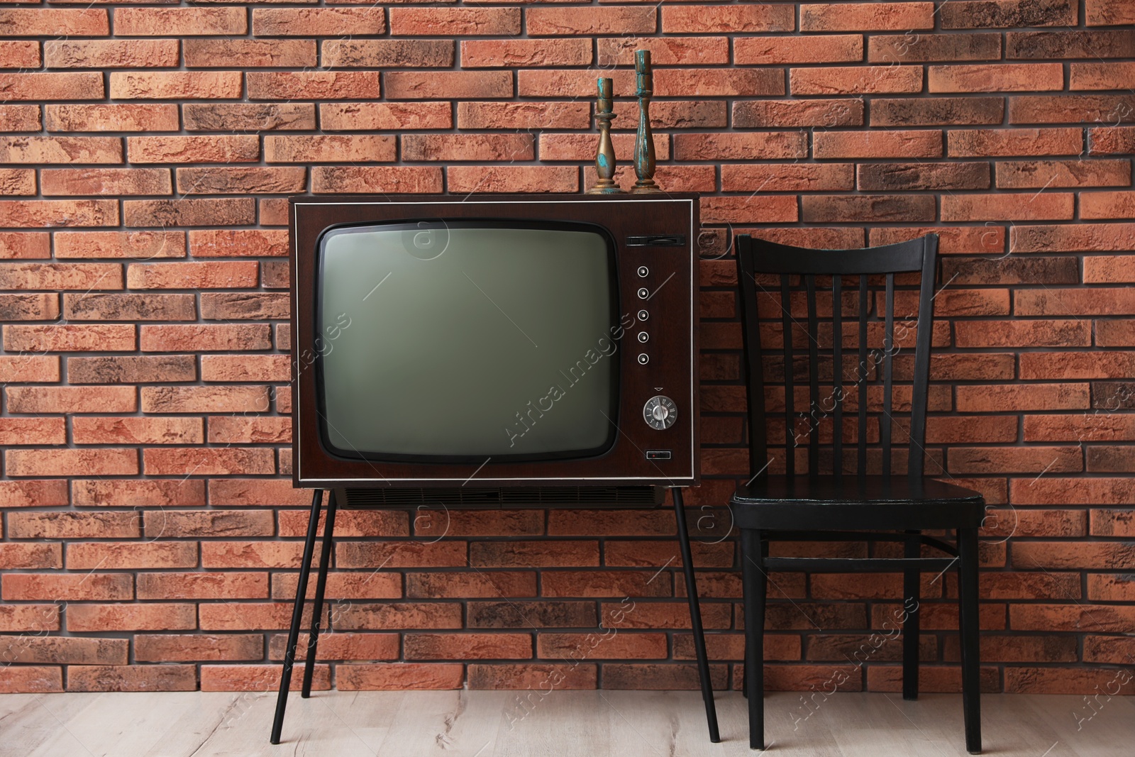 Retro TV on stand and black chair near red brick wall. Used stuff Photo of Retro TV on stand and black chair near red brick wall. Used stuff