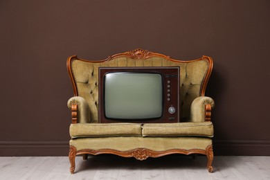 Photo of Retro TV on sofa near brown wall. Used stuff
