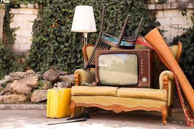 Photo of Retro TV on sofa and other used stuff outdoors