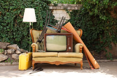 Photo of Retro TV on sofa and other used stuff outdoors