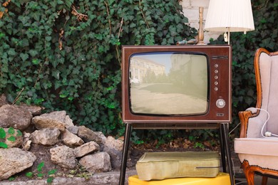 Photo of Retro TV on stand, suitcases and other used stuff outdoors. Space for text