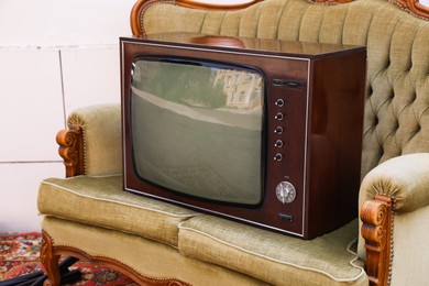 Photo of Retro TV on sofa and carpet near white wall outdoors. Used stuff