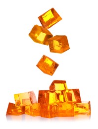 Image of Yummy orange jelly cubes falling on white background