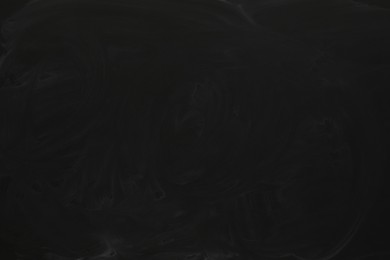 Photo of Chalk rubbed out on black chalkboard as background, closeup. Space for text