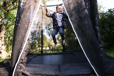Photo of Cute little boy jumping on black trampoline outdoors