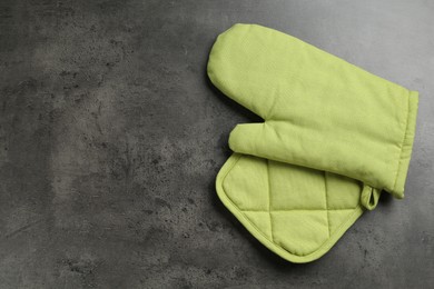 Photo of Green oven glove and potholder on dark textured table, top view. Space for text
