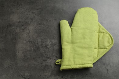 Photo of Green oven glove and potholder on dark textured table, top view. Space for text
