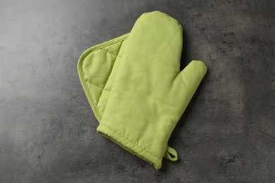 Photo of Green oven glove and potholder on dark textured table, top view