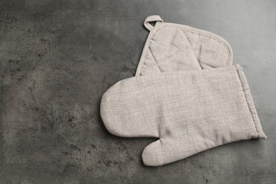 Photo of Grey oven glove and potholder on dark textured table, top view. Space for text