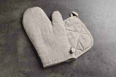 Photo of Grey oven glove and potholder on dark textured table, top view