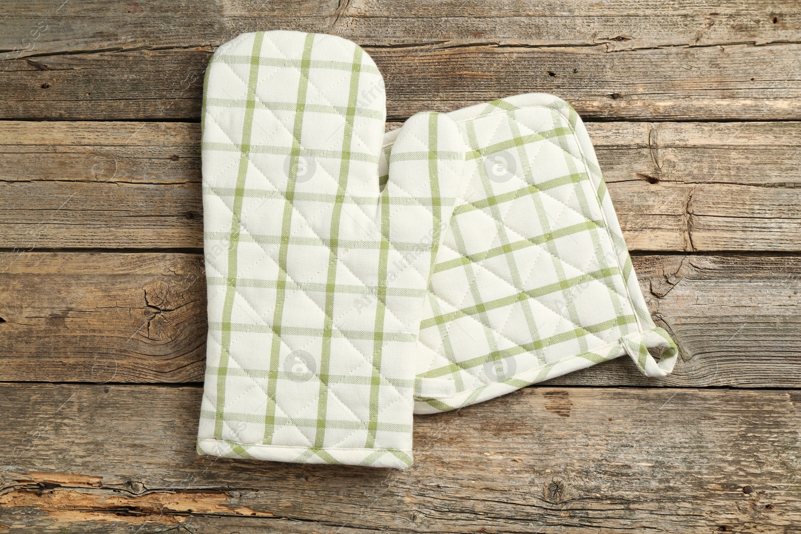 Photo of Oven glove and potholder on wooden table, top view